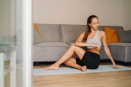 Woman practicing yoga indoors on a mat, embodying fitness and tranquility.