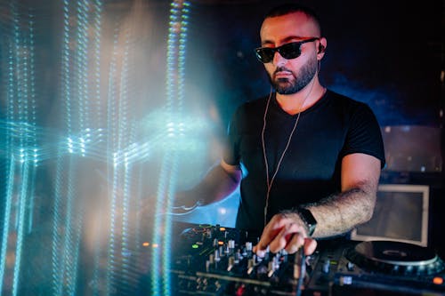 A Disc Jockey Wearing Earphones and Sunglasses on a Nightclub