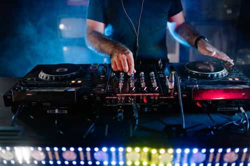 Free DJ performing with mixing equipment at a nightclub, vibrant nightlife scene. Stock Photo