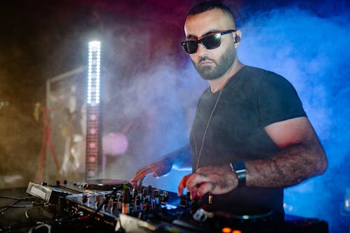 Man in Black T-shirt and Black Sunglasses Using Audio Mixer