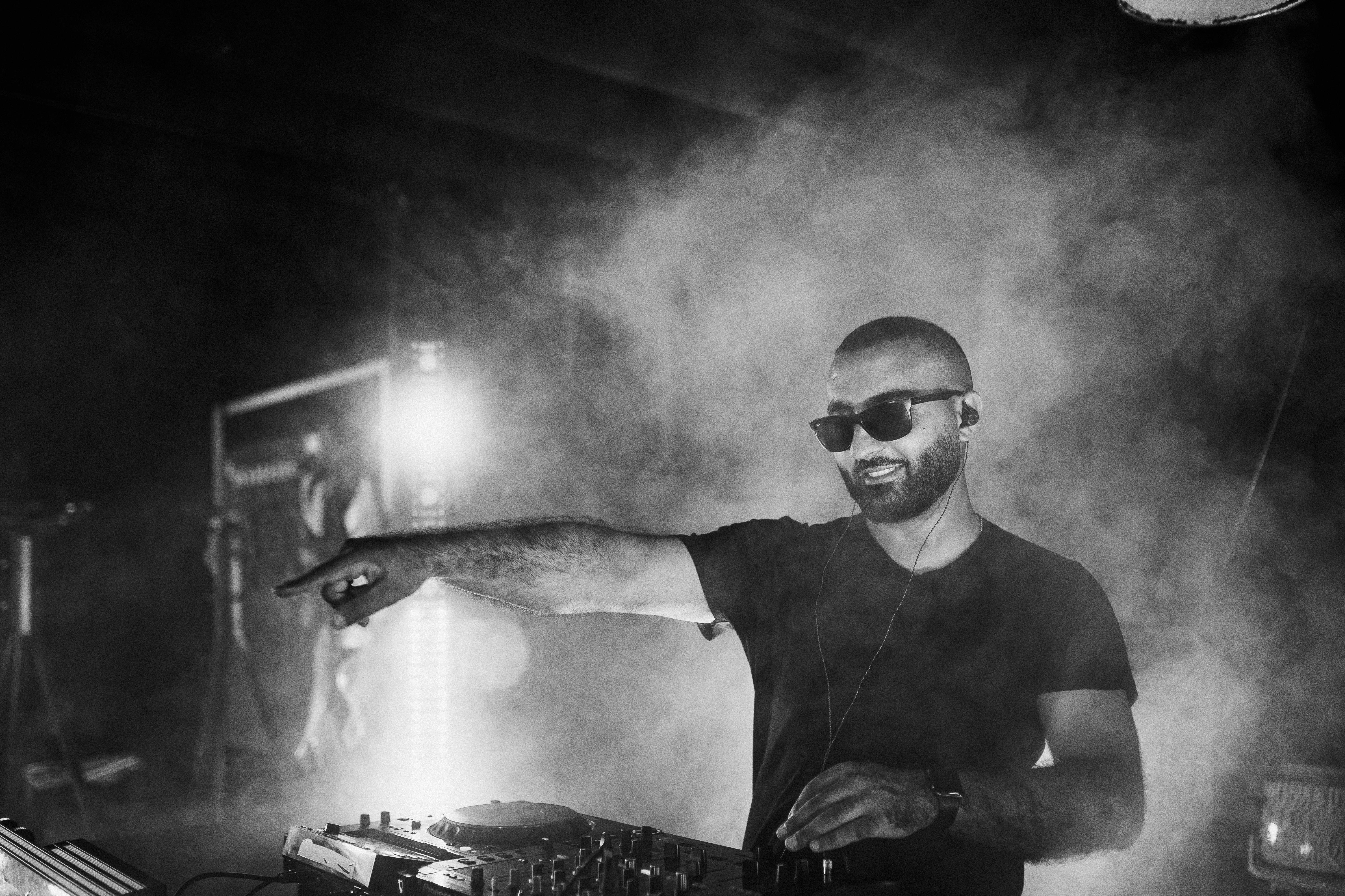 man in black t shirt and sunglasses smiling and pointing finger to the audience