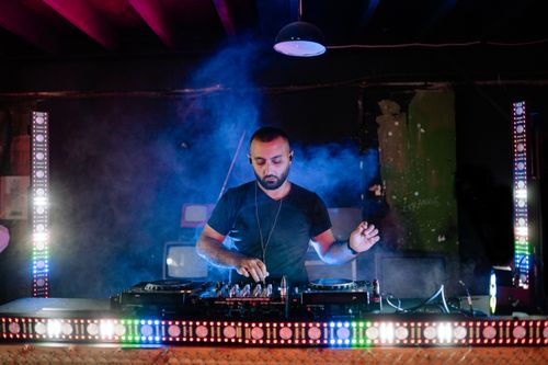 Free DJ mixing tracks under colorful lights in a lively nightclub atmosphere. Stock Photo