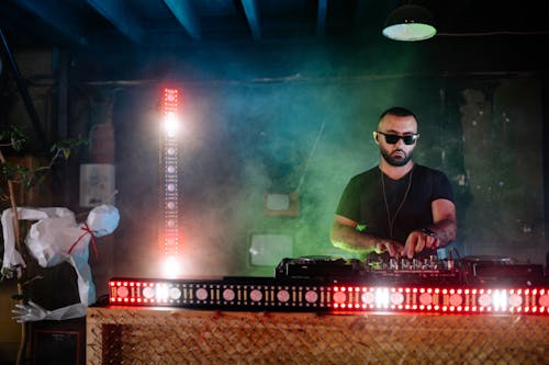 A Disc Jockey Performing on a Nightclub while Wearing Shades