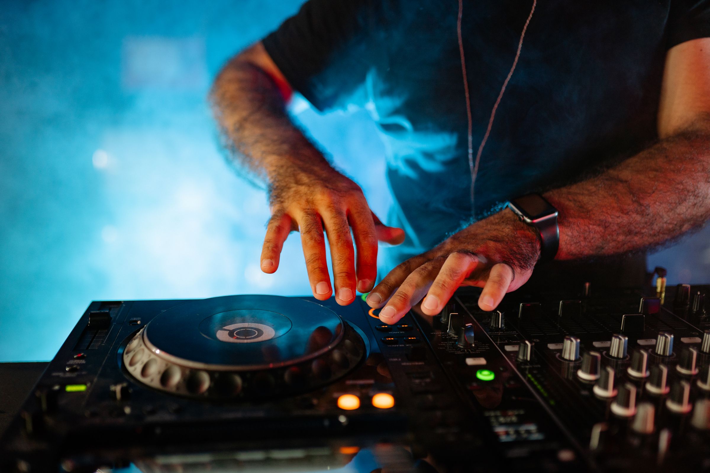 A DJ skillfully mixes music on a professional mixer in a vibrant nightclub setting