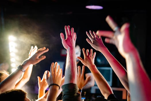 Vibrant crowd raising hands at a concert with dynamic lighting, capturing nightlife energy.