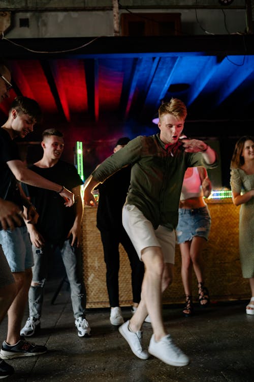 Free A Man in Green Long Sleeve Shirt  and Shorts Surrounded with People Dancing Stock Photo