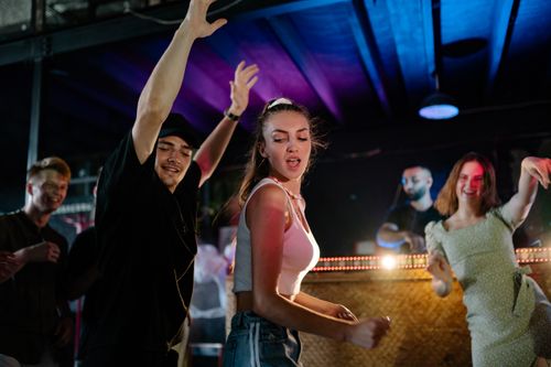Free Lively group of adults dancing energetically at a nightclub with vibrant lights. Stock Photo