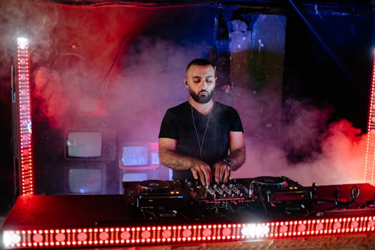 A DJ performs at a nightclub with vibrant lights and smoke effects, creating an electrifying atmosphere.