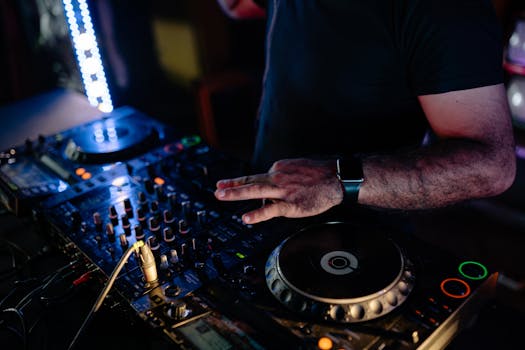 A DJ mixes music on a mixer in a vibrant nightclub setting, creating an energetic atmosphere.