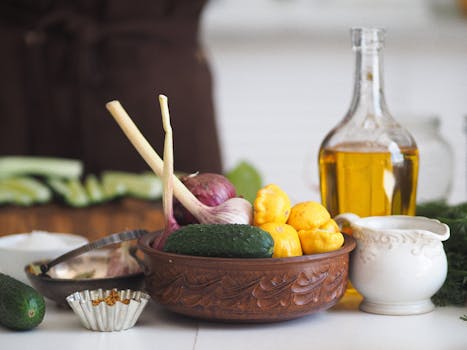 A rustic still life featuring cucumbers, garlic, and olive oil arranged with kitchen essentials.