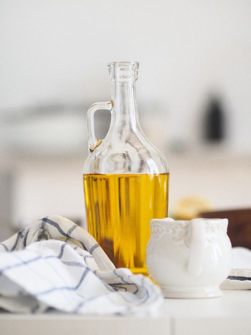 Free Aesthetic kitchen still life featuring olive oil in glass bottle with ceramic cup and cloth. Stock Photo