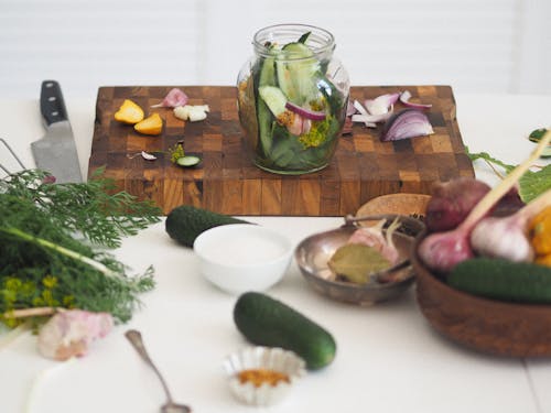 A Glass Jar with Fresh Vegetables on a Wooden Chopping Board