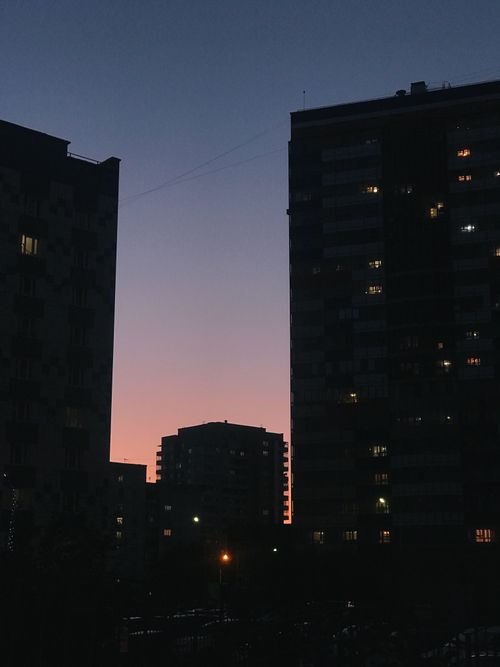 Free A beautiful city skyline silhouette against a colorful dusk sky with glowing lights. Stock Photo
