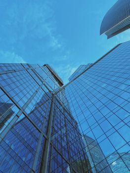 Stunning architectural low angle view of modern skyscrapers with reflective glass windows against a clear blue sky.