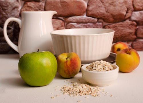 Free Green Apple Beside White Ceramic Bowl with Oats Stock Photo