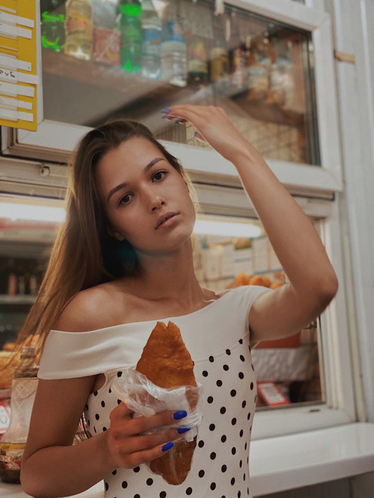 A Woman In White Off Shoulder Top Holding A Food