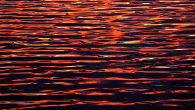 Captivating view of ripples on water reflecting vibrant sunset colors.