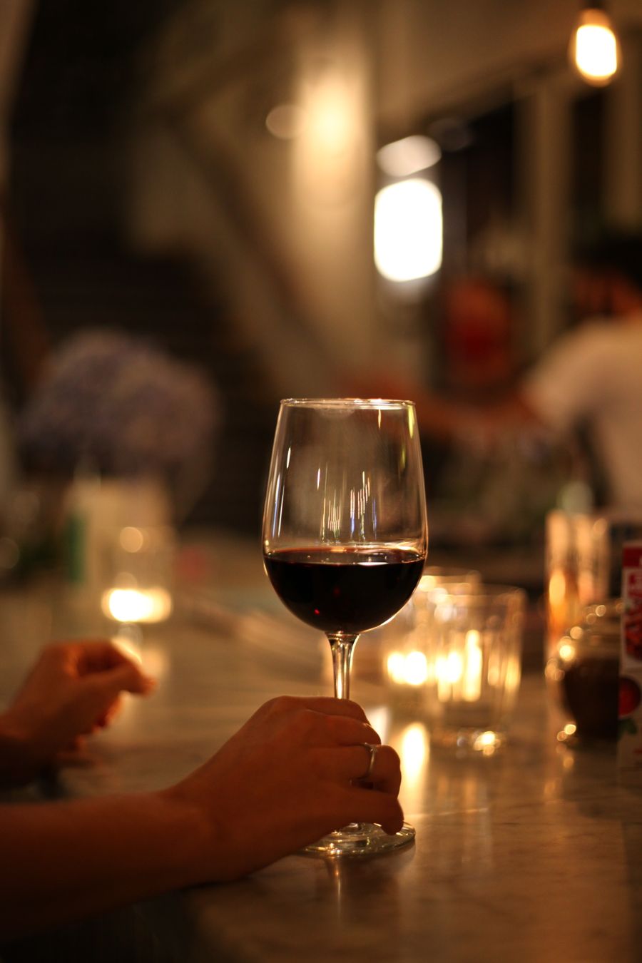 A glass of deep red wine held in candlelight
