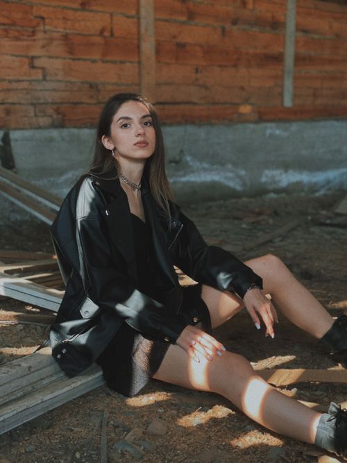 Free A fashionable woman in a leather jacket poses with confidence outdoors, showcasing style and elegance. Stock Photo