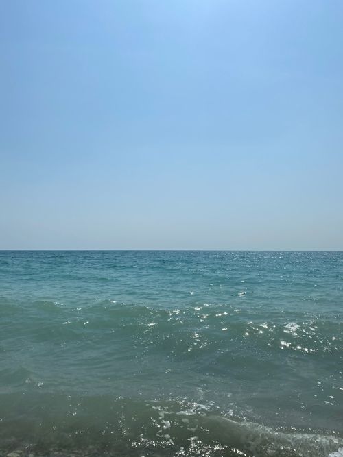 Free Calm ocean waves meeting the horizon under a clear blue sky, evoking tranquility. Stock Photo