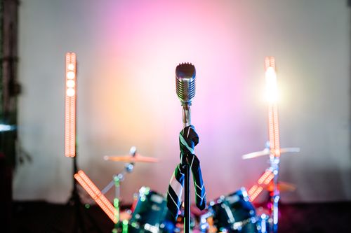 Free Retro microphone on a stage with colorful lights and a drum set, perfect for music themes. Stock Photo