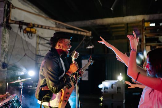 A Man in Black Leather Jacket Singing on Stage