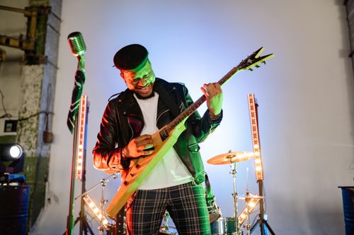 Free A dynamic musician playing an electric guitar during a live performance indoors. Stock Photo