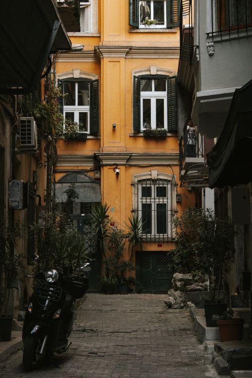 Free A quaint alley in Istanbul featuring a yellow building with plants and a parked motorbike. Stock Photo