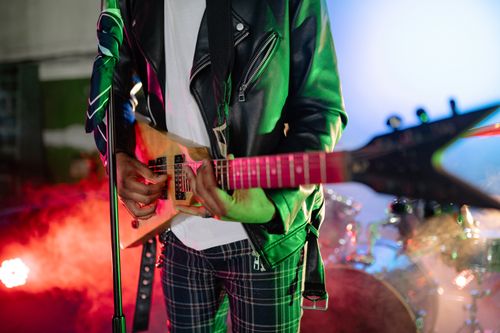 Free Dynamic close-up of a musician playing an electric guitar with vibrant stage lights. Stock Photo