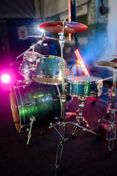 Dynamic close-up of a drum set with colorful stage lighting creating an energetic atmosphere.