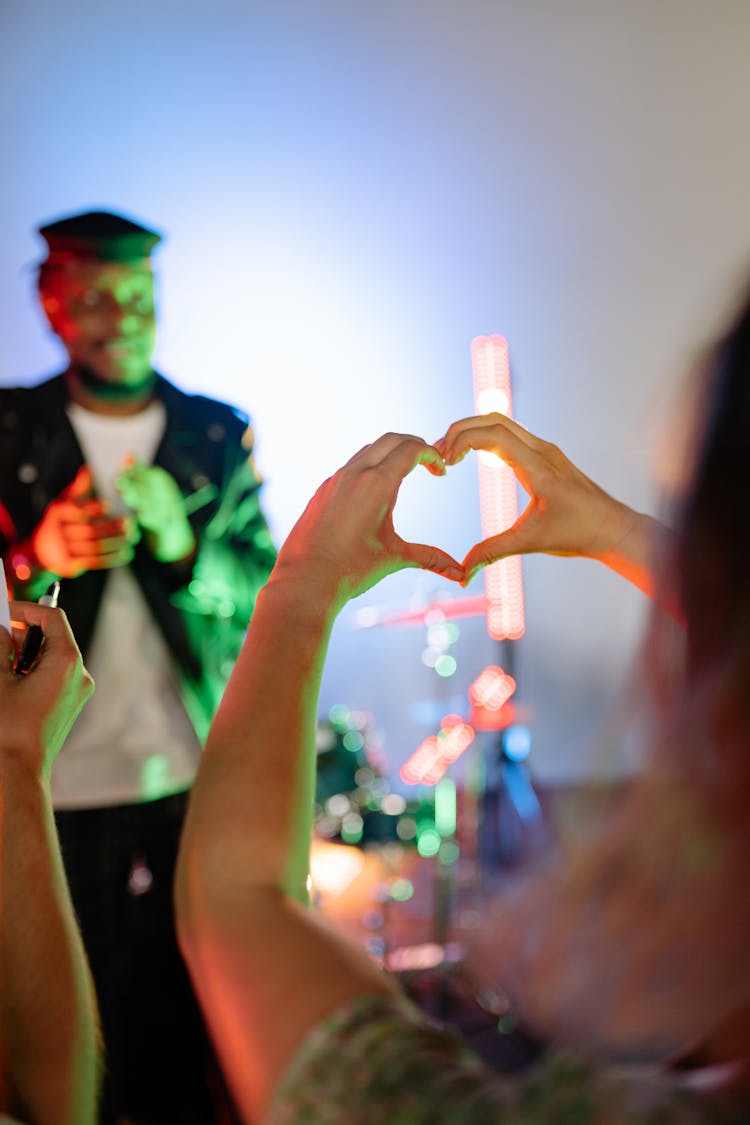 Woman Making Heart Shape With Hands In Concert