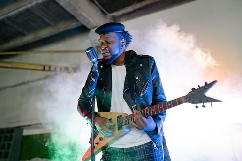 Free Musician rocking an electric guitar on stage with dramatic lighting and smoke effects. Stock Photo