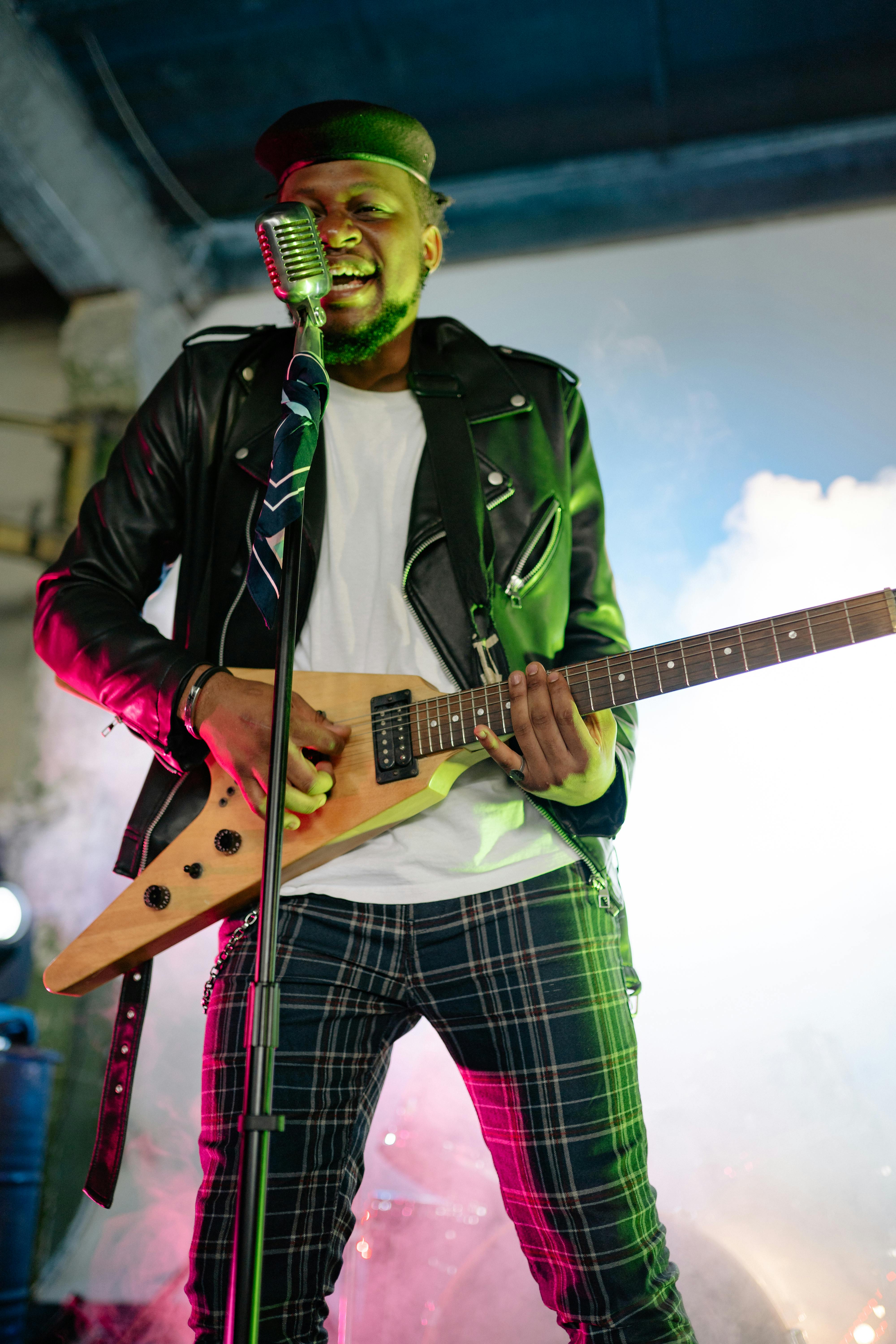 African American man performing with guitar in lively concert setting.