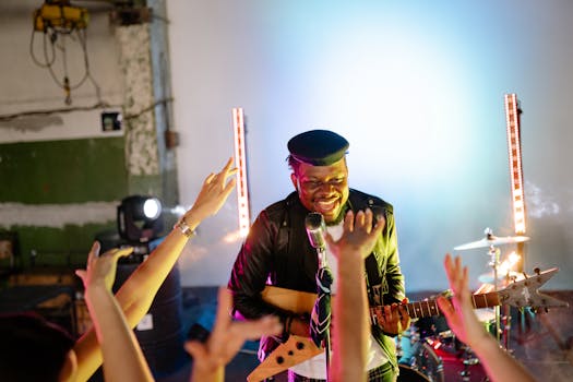 Musician performing energetically on stage with a guitar, engaging the lively audience.