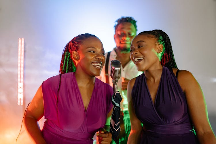 Women In Purple Top Smiling While Singing Together