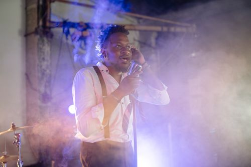 Free A performer passionately singing into a vintage microphone amidst atmospheric smoke. Stock Photo