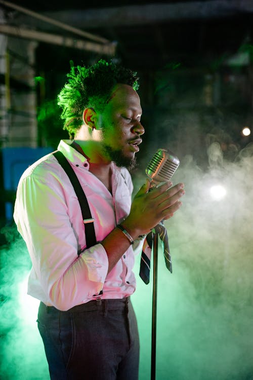 Free A Man Holding a Microphone While Singing on a Stage with Smoke Effects Stock Photo