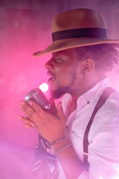 A side view of an African American man passionately singing into a vintage microphone.