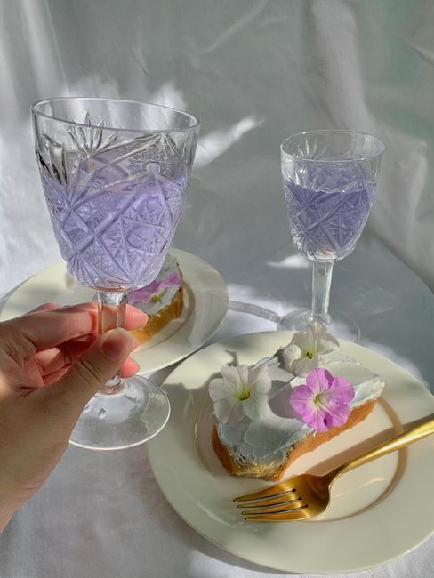 A beautiful brunch scene featuring floral-topped toast and lavender drinks in crystal glasses.