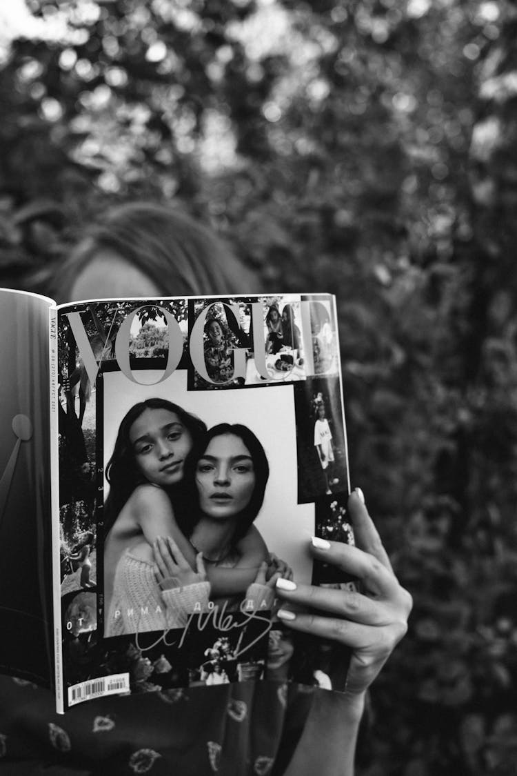 Grayscale Photo Of A Woman Holding A Vogue Magazine