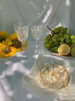 Elegant still life featuring cheese, grapes, and crystal glasses with sunflowers.