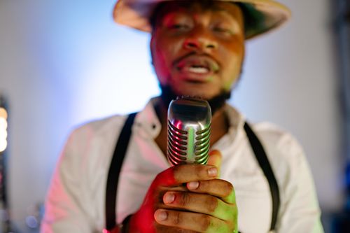Free Close-up of a male singer holding a vintage microphone in a studio setting. Stock Photo
