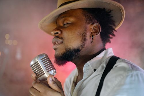 Free A male singer passionately performing indoors with a vintage microphone. Stock Photo