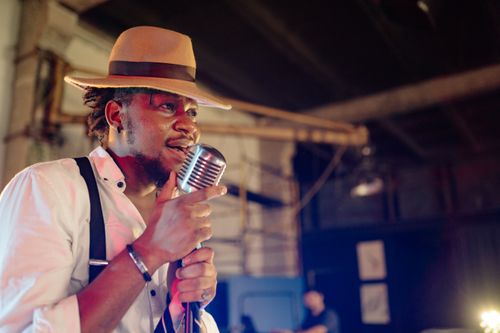 Free African American male vocalist performing on stage, holding a vintage microphone. Stock Photo