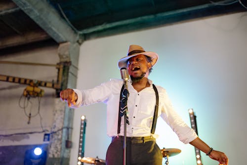 Free A Man in White Button Up Shirt and Brown Hat Singing and Dancing Stock Photo
