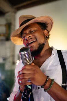 A male singer passionately performs with a microphone indoors, capturing the essence of live music.