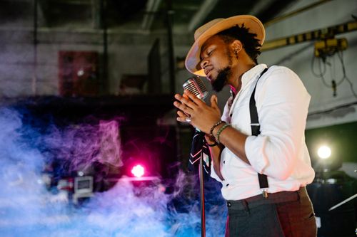 Free An African American singer performs passionately on stage, illuminated by colorful lights. Stock Photo