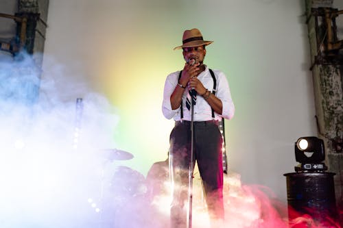 Free A Man in White Long Sleeve Shirt and Brown Hat Singing on Stage Stock Photo