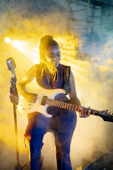 An engaging performance with a female guitarist enveloped in vibrant stage lights and smoke.