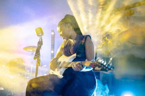A Woman Singing While Playing the Electric Guitar 